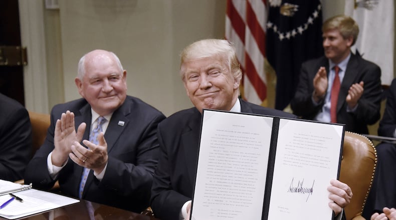 President Donald Trump signs the Executive Order Promoting Agriculture and Rural Prosperity in America as Agriculture Secretary Sonny Perdue looks on during a meeting with farmers on April 25, 2017, in the Roosevelt Room of the White House in Washington, D.C. Perdue was one of only a few Cabinet members to serve in their roles through the Trump administration. (Olivier Douliery/Abaca Press/TNS)