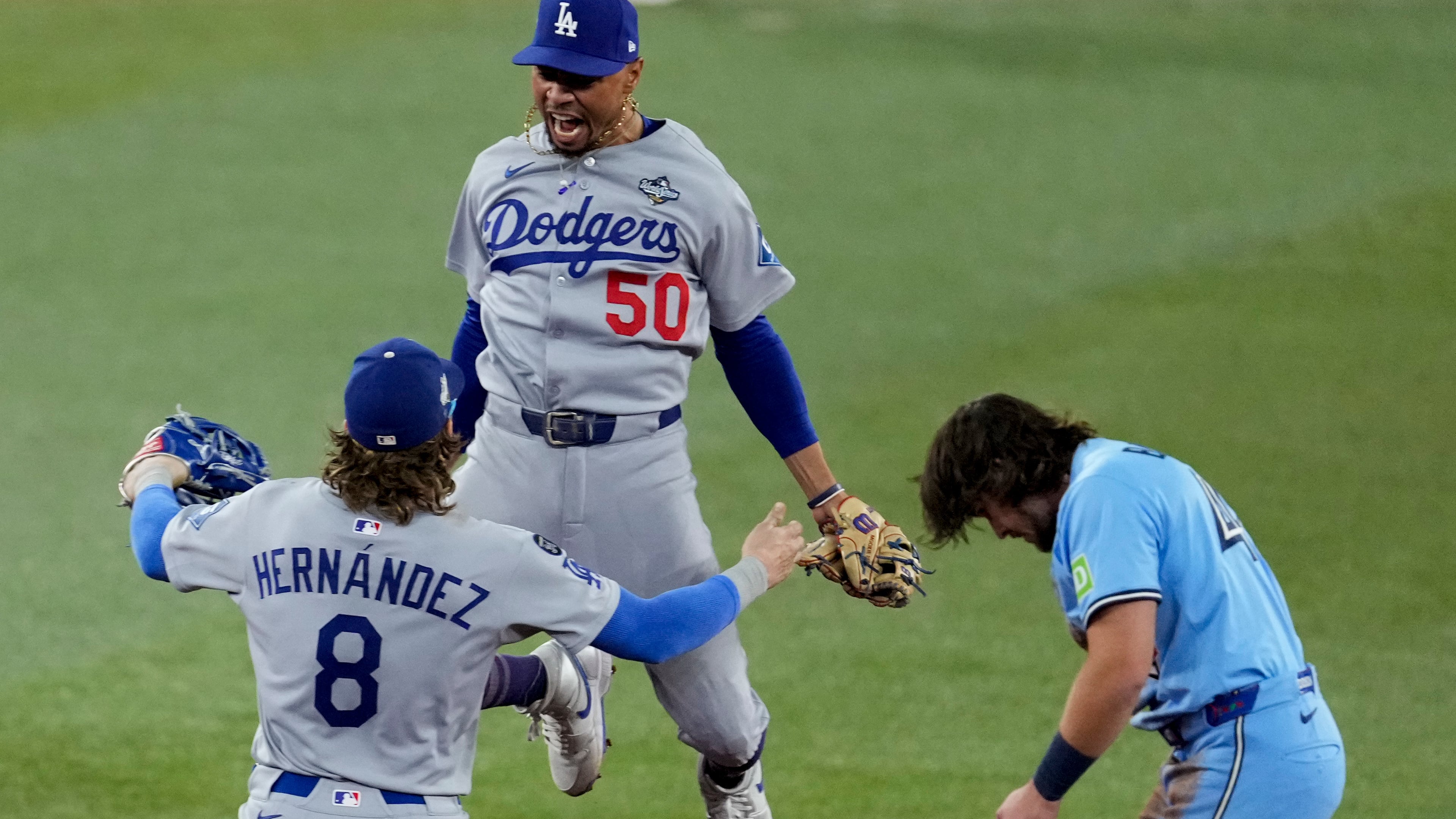 Los Angeles Dodgers' Mookie Betts (50) leaps into the arms of Kiké Hernández (8) after Toronto Blue Jays' Addison Barger, right, was forced out to end Game 6 of baseball's World Series, Friday, Oct. 31, 2025, in Toronto. (AP Photo/Ashley Landis)