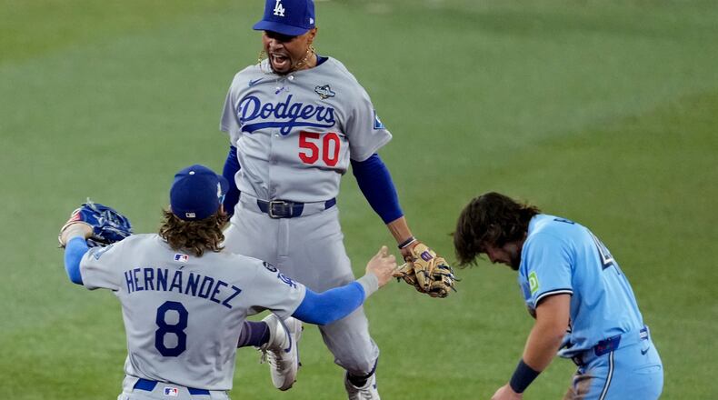 Los Angeles Dodgers' Mookie Betts (50) leaps into the arms of Kiké Hernández (8) after Toronto Blue Jays' Addison Barger, right, was forced out to end Game 6 of baseball's World Series, Friday, Oct. 31, 2025, in Toronto. (AP Photo/Ashley Landis)