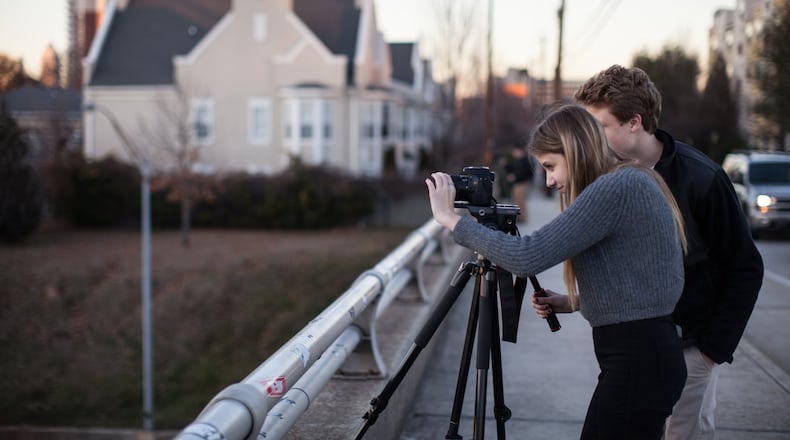 Sydney Lord, left, and her brother Sam Lord record video footage of the Atlanta skyline from the Jackson Street Bridge at sunset, Wednesday, Jan. 28, 2015, in Atlanta. Experienced local photographers may consider the view from the bridge a little cliche, but that doesn’t stop them from returning to it for a better shot. (SPECIAL/BRANDEN CAMP)