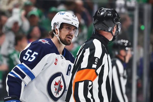 Winnipeg Jets' Mark Scheifele (55) talks to referee Dan O'Rourke (9) after Scheifele was issed a tripping penalty in the third period of Game 6 of a second-round NHL hockey playoff series against the Dallas Stars in Dallas, Saturday, May 17, 2025. (AP Photo/Gareth Patterson)