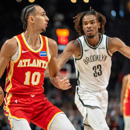 Atlanta Hawks forward Zaccharie Risacher (10), left, attempts to pass the ball against Brooklyn Nets center Nic Claxton (33) during the first half of an NBA basketball game, Sunday, Feb. 22, 2026, in Atlanta. (AP Photo/Erik Rank)