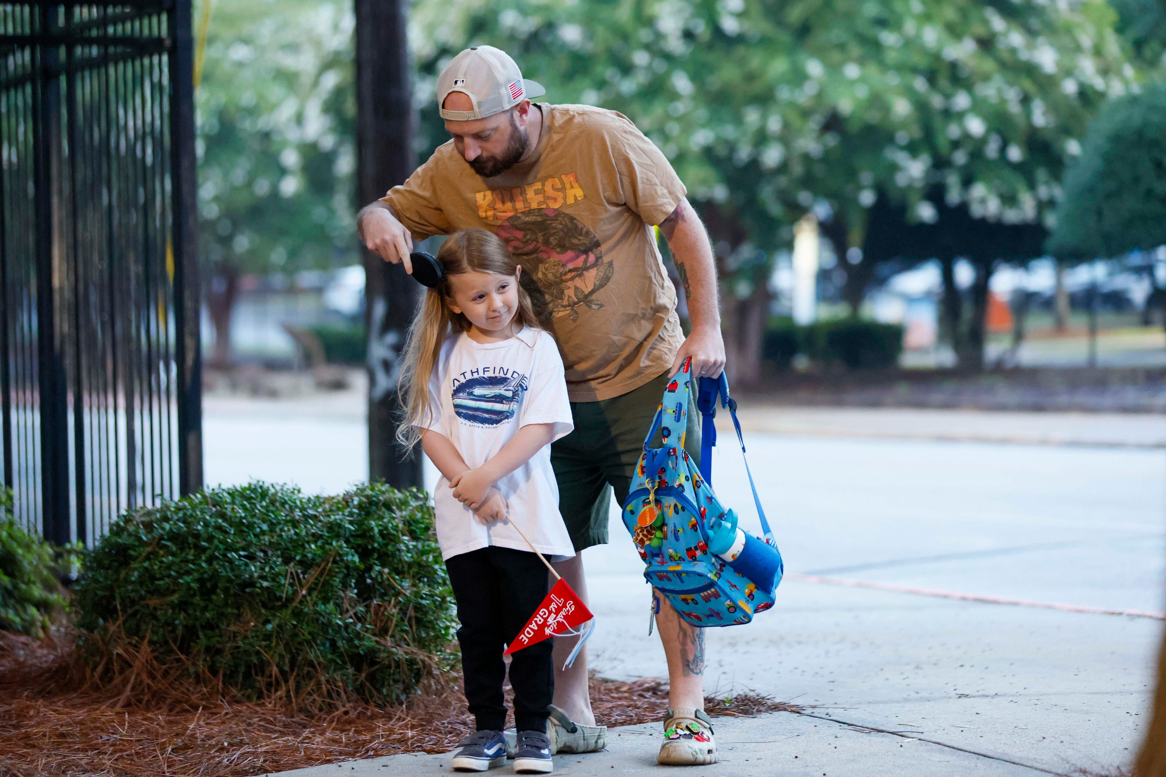 You can't start the school year with messy locks, so Rich Creavy brushes the hair of a third grader RJ Creavy before they enter Hope-Hill Elementary on Monday. (Miguel Martinez/AJC)