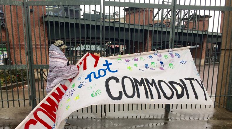 Peoplestown resident Sherise Brown fixes a sign that reads “Community not Commodity” that had been knocked down by the weather outside Turner Field on Monday.J. Scott Trubey/strubey@ajc.com