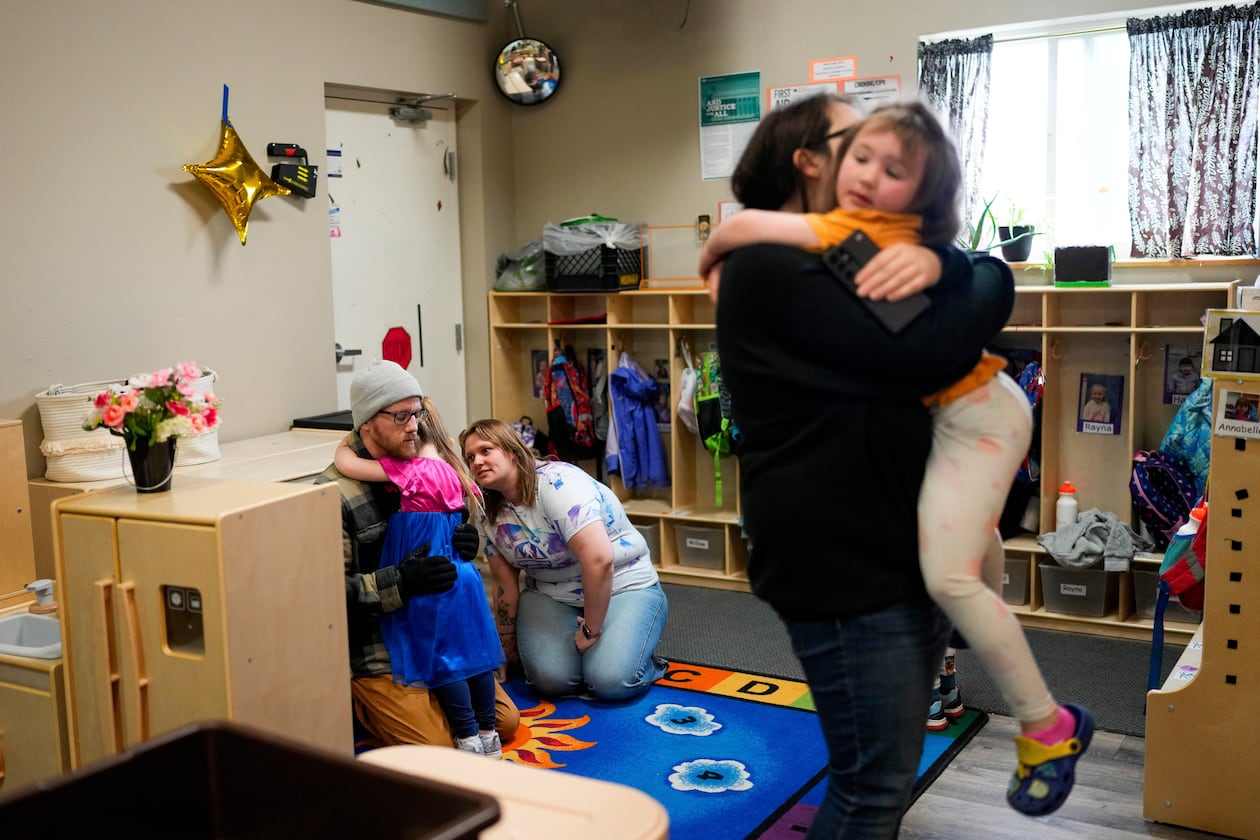 FILE - Olivia Starr clings to her father, Thaxter Hall, as Associate Educator Jessica Clark works to comfort her as she is dropped off for the last day of school at the Meadow Lakes CCS Early Learning, a Head Start center, May 8, 2024, in Wasilla, Alaska. (AP Photo/Lindsey Wasson, File)