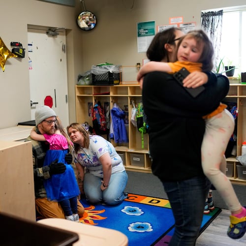 FILE - Olivia Starr clings to her father, Thaxter Hall, as Associate Educator Jessica Clark works to comfort her as she is dropped off for the last day of school at the Meadow Lakes CCS Early Learning, a Head Start center, May 8, 2024, in Wasilla, Alaska. (AP Photo/Lindsey Wasson, File)