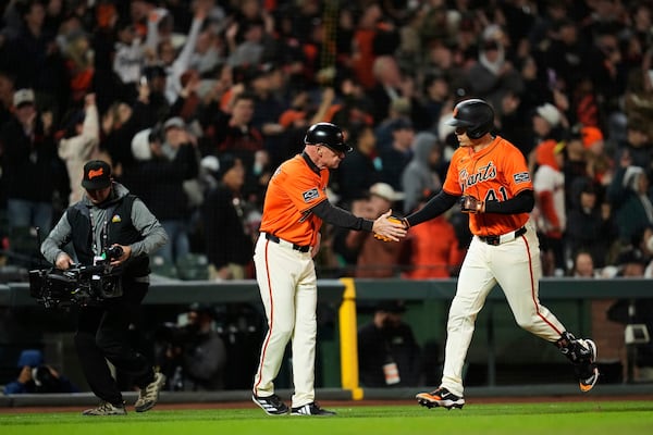 San Francisco Giants' Wilmer Flores, right, celebrates with third base coach Matt Williams after hitting a three-run home run during the sixth inning of a baseball game against the Athletics, Friday, May 16, 2025, in San Francisco. (AP Photo/Godofredo A. Vásquez)