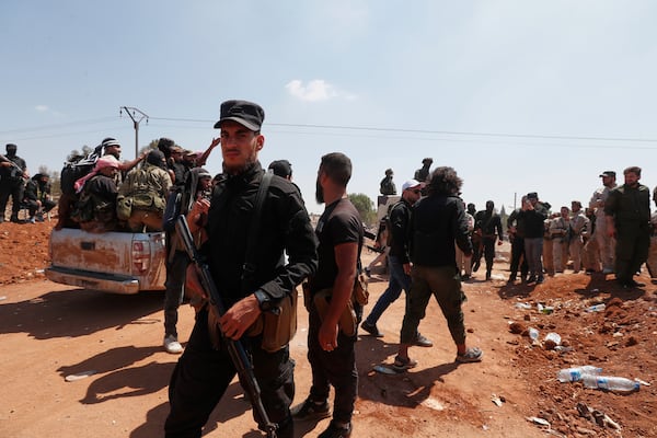 Syrian government security forces block Bedouin fighters, background, from entering Sweida province, in Busra al-Harir village, southern Syria, Sunday, July 20, 2025. (AP Photo/Omar Sanadiki)