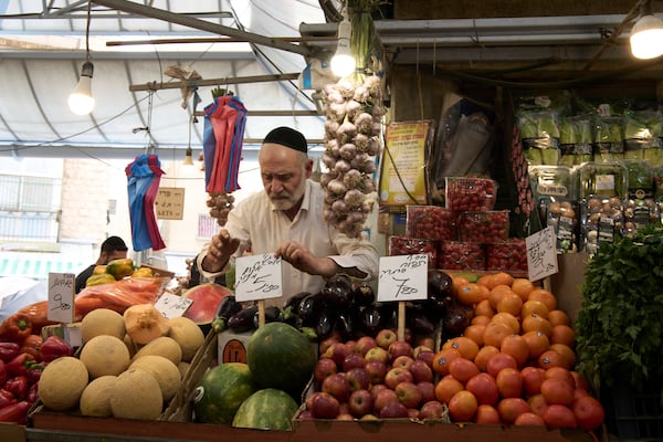 An Israeli shopkeeper places a price tag for his watermelon at his fruit and vegetable stall in the Machane Yehuda Market in Jerusalem, Israel, Tuesday, April 8, 2025. (AP Photo/Maya Alleruzzo)