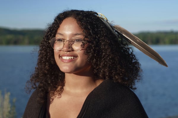 Jayvionna Buck poses for a portrait by the Mississippi River with the new bald eagle feather she received at a ceremony honoring high school graduates like her at the Prairie Island Indian Community in Minnesota on Wednesday, July 9, 2025. (AP Photo/Mark Vancleave)