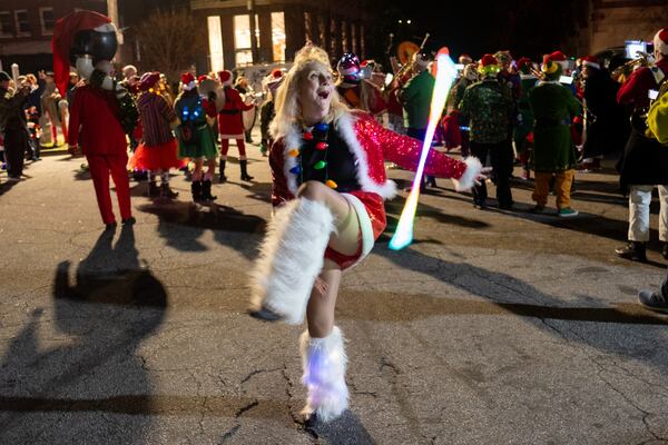 Christine Daniel twirls a baton with the Seed & Feed Marching Abominable band during Atl SantaCon in Little Five Points on Saturday, Dec. 20, 2025. (Ben Gray for the AJC)