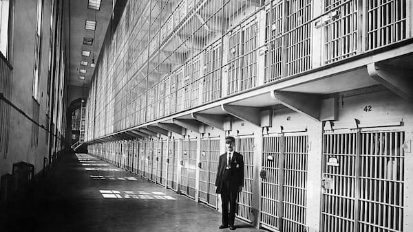 A guard at the Reformatory is photographed in 1911 with the tiers of cell blocks shown over his head and the cavernous prison stretching out behind him. 