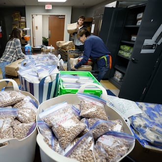 Volunteers with the Latin American Association — including Ellen Goldwasser (left), Nick Nele (center) and Ellen Levitt — are seen organizing boxes and bags of food in 2025. The organization is dedicated to empowering individuals and families through education, workforce development, immigration services and community engagement. (Miguel Martinez/AJC)
