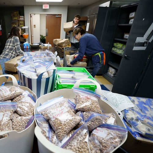 Volunteers with the Latin American Association — including Ellen Goldwasser (left), Nick Nele (center) and Ellen Levitt — are seen organizing boxes and bags of food in 2025. The organization is dedicated to empowering individuals and families through education, workforce development, immigration services and community engagement. (Miguel Martinez/AJC)