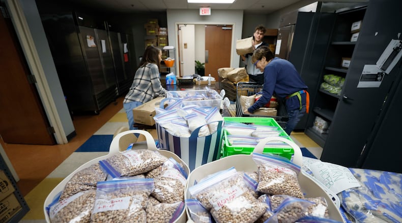 Volunteers with the Latin American Association — including Ellen Goldwasser (left), Nick Nele (center) and Ellen Levitt — are seen organizing boxes and bags of food in 2025. The organization is dedicated to empowering individuals and families through education, workforce development, immigration services and community engagement. (Miguel Martinez/AJC)
