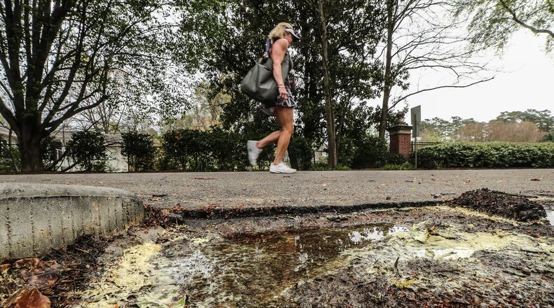 Renee Houle walks by a puddle full of pollen on Lionel Lane in Atlanta. JOHN SPINK / JSPINK@AJC.COM