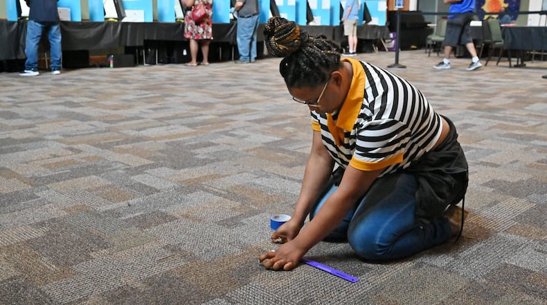 Kasharri Blacknell, a poll worker, places tape indicators for maintaining social distancing as Gwinnett County residents cast their votes June 9 during the Georgia primary elections at Pleasant Hill Presbyterian Church in Duluth. (Hyosub Shin / Hyosub.Shin@ajc.com)