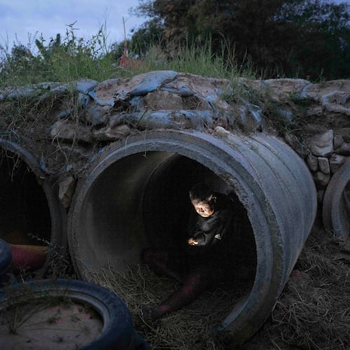 A Thai resident who fled clashes between Thai and Cambodian soldiers, uses mobile phone while taking shelter in Buriram province, Thailand, Tuesday, Dec. 9, 2025. (AP Photo/Wason Wanichakorn)