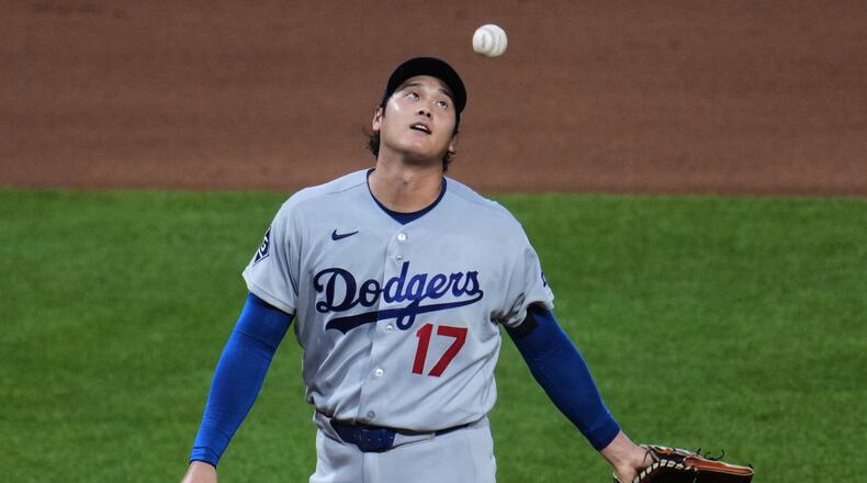 Los Angeles Dodgers two-way player Shohei Ohtani waits to hand the ball to manager Dave Roberts, after giving up a two-run double to Pittsburgh Pirates' Brandon Lowe during the seventh inning of a baseball game in Pittsburgh, Wednesday, June 10, 2026. (AP Photo/Gene J. Puskar)