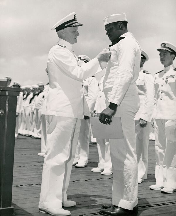 Admiral Chester W. Nimitz, USN, Commander-in-Chief, Pacific Fleet, pins the Navy Cross on Doris Miller, Steward's Mate 1/c, USN, at a ceremony on board a U.S. Navy warship in Pearl Harbor, T.H., May 27, 1942. (Library of Congress)