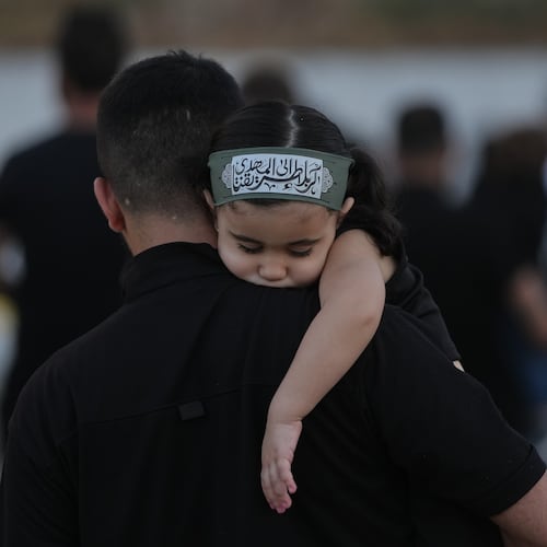 A girl wearing an Ashoura headband rests on her father's shoulder during a sermon marking the third day of Ashoura, the Shiite Muslim commemoration of the 7th-century death of Imam Hussein, the grandson of the Prophet Muhammad, in the southern port city of Tyre, Lebanon, Friday, June 19, 2026. (AP Photo/Hassan Ammar)