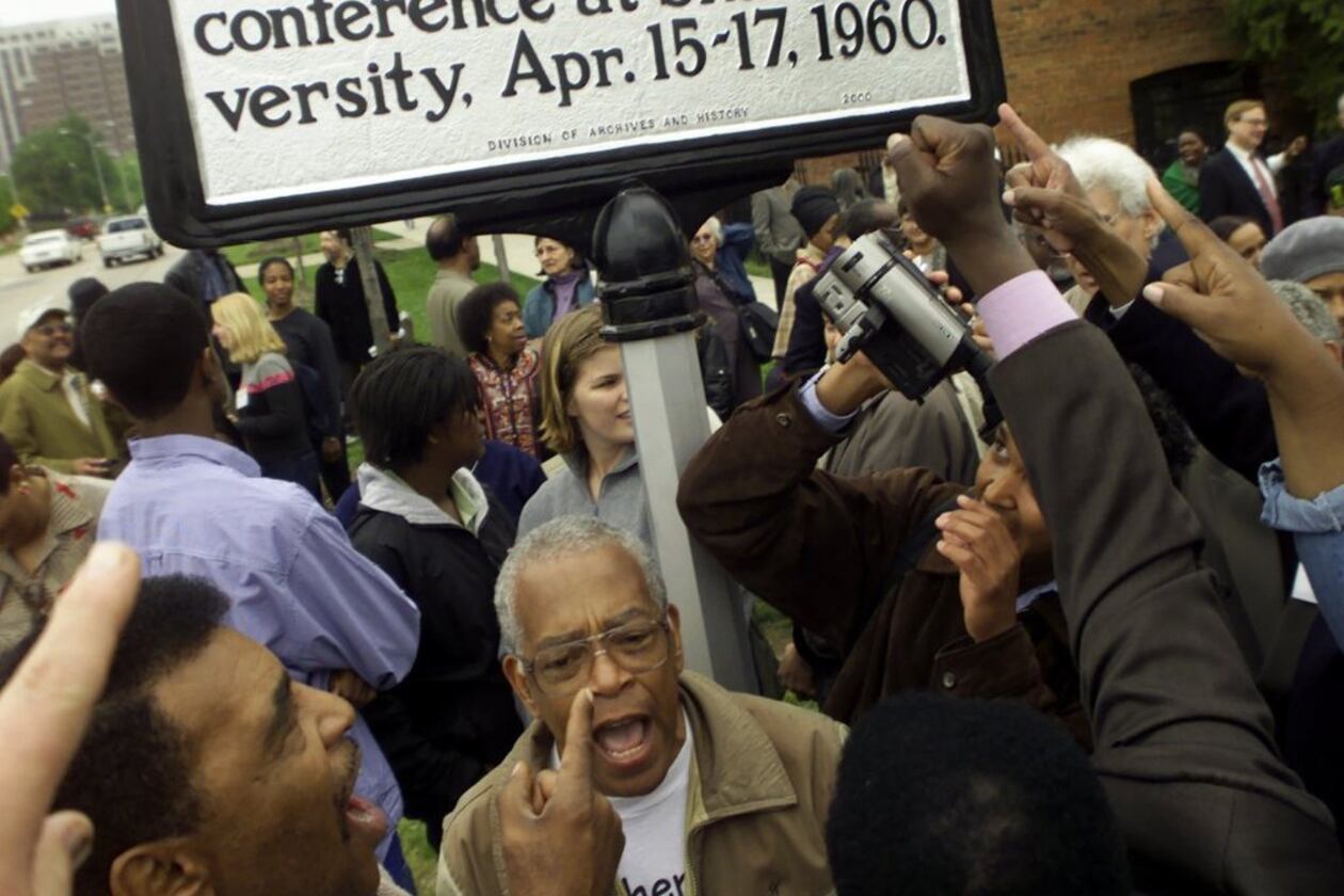 Supporters rally and sing around the unveiling of a historical marker honoring the Student Nonviolent Coordinating Committee (SNCC) on the Shaw University campus in Raleigh, N.C., on April 14, 2000. Prominent in the photo are Chuck Neblett, lower left, and Jim Foreman, beneath marker. (Photo by CHRISTOBAL PEREZ/Raleigh News and Observer)