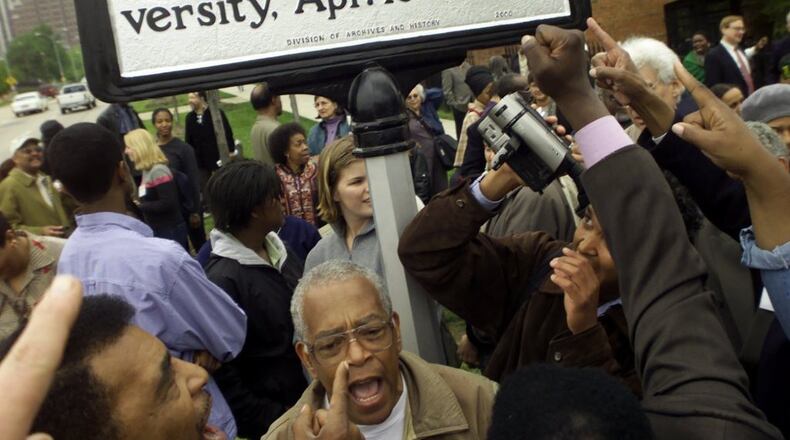Supporters rally and sing around the unveiling of a historical marker honoring the Student Nonviolent Coordinating Committee (SNCC) on the Shaw University campus in Raleigh, N.C., on April 14, 2000. Prominent in the photo are Chuck Neblett, lower left, and Jim Foreman, beneath marker. (Photo by CHRISTOBAL PEREZ/Raleigh News and Observer)