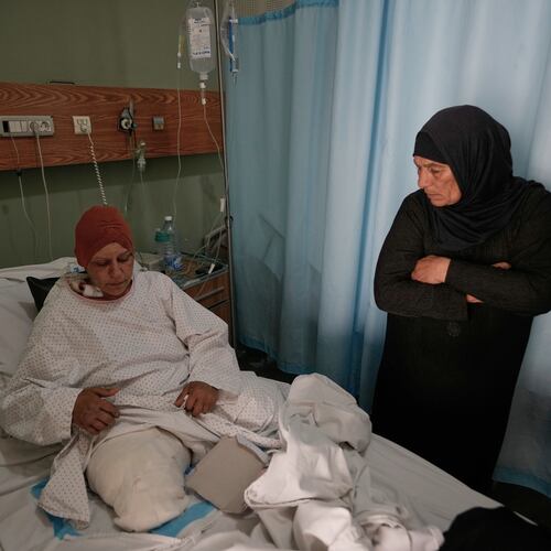 Sanaa Khalil, 35, a Syrian farmer who lost her two legs in the past days by an Israeli airstrike while she was working at a banana plantation, lies on a bed as she is assisted by a relative at a hospital in the southern port city of Tyre, Lebanon, Friday, May 1, 2026. (AP Photo/Hussein Malla)