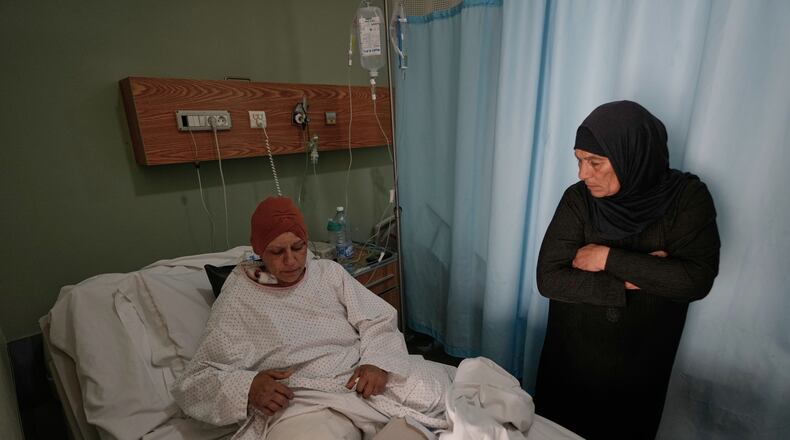 Sanaa Khalil, 35, a Syrian farmer who lost her two legs in the past days by an Israeli airstrike while she was working at a banana plantation, lies on a bed as she is assisted by a relative at a hospital in the southern port city of Tyre, Lebanon, Friday, May 1, 2026. (AP Photo/Hussein Malla)