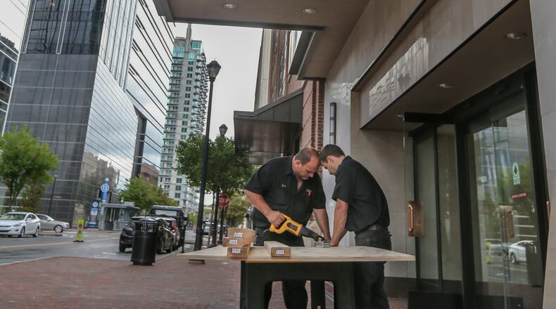 Workers begin to repair damage Tuesday after burglars smashed into the Dillard’s department store at Atlantic Station early Tuesday, making off with nearly $35,000 in high-dollar jeans and hoodies. JOHN SPINK / JSPINK@AJC.COM