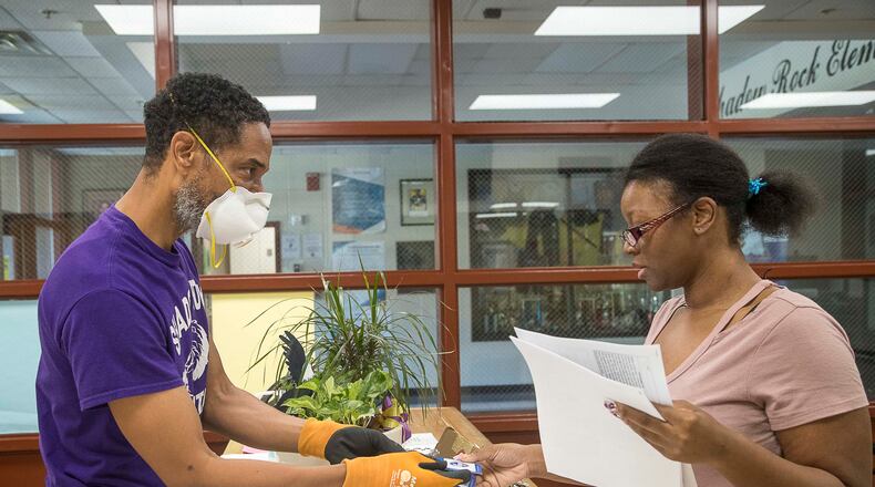 Shadow Rock Elementary School Assistant Principal Jason Moffitt is masked as he gives parent Shadiyah Williams handouts during her visit to pick up her child’s classwork at the school in Lithonia April 27, 2020. Employees returning to school buildings in the district must wear masks as part of efforts to continue slowing the spread of the coronavirus. (ALYSSA POINTER / ALYSSA.POINTER@AJC.COM)