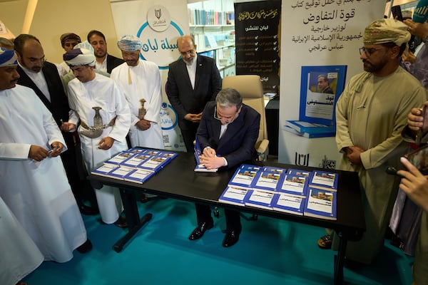 Iranian Foreign Minister Abbas Araghchi, signs copies of his book "The Power of Negotiation" at the Muscat International Book Fair in Oman, Friday, April 25, 2025. (AP Photo/ Fatima Shbair)