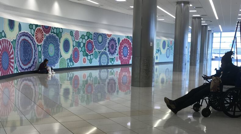 The decorative wall at the center of Concourse C at Hartsfield-Jackson International Airport is where a food court is supposed to be, but contracting delays leave it empty.