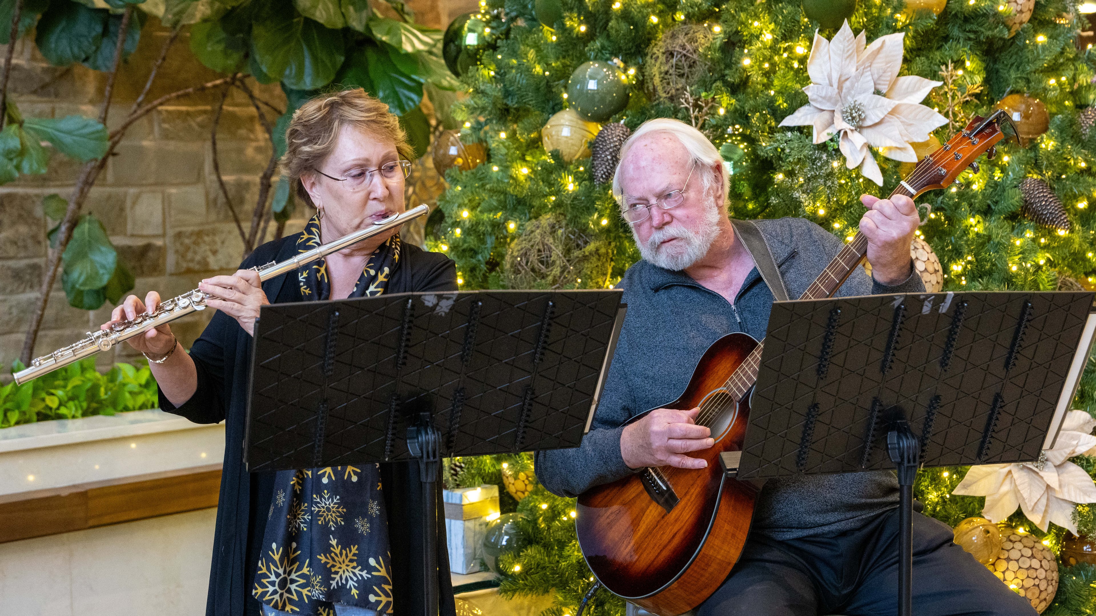 Barb Russell and David Walter play Christmas songs in the lobby of Wellstar East Cobb Health Park in Marietta. They were both widowed and met online. (Phil Skinner for the AJC)