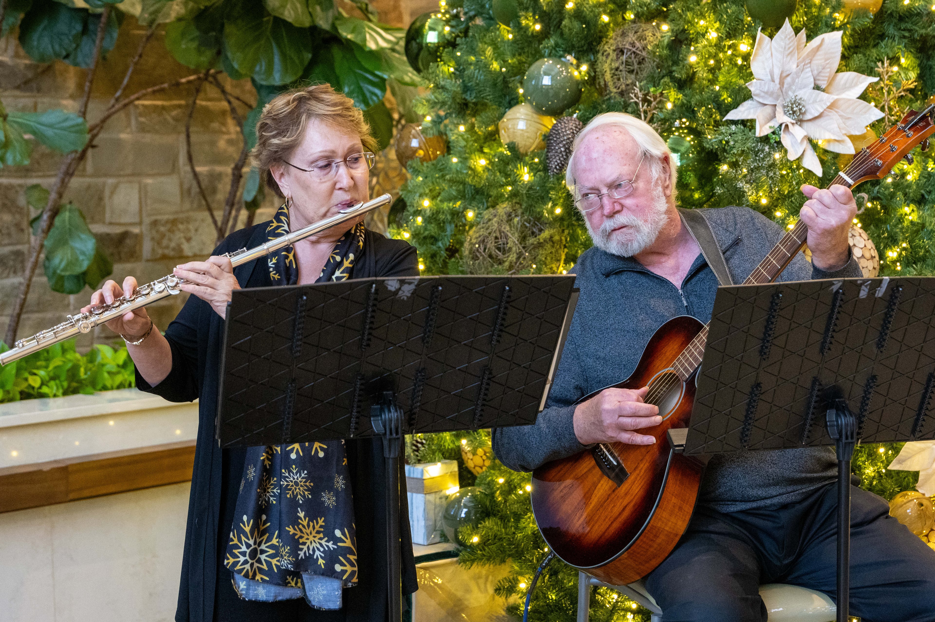 Barb Russell and David Walter play Christmas songs in the lobby of Wellstar East Cobb Health Park in Marietta. They were both widowed and met online. (Phil Skinner for the AJC)