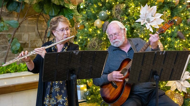 Barb Russell and David Walter play Christmas songs in the lobby of Wellstar East Cobb Health Park in Marietta. They were both widowed and met online. (Phil Skinner for the AJC)