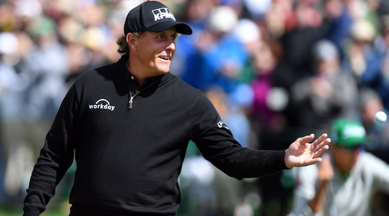Phil Mickelson toss his ball to caddie following an eagle on the second green in last year’s Masters at the Augusta National Golf Club. BRANT SANDERLIN / SPECIAL