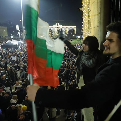 Students wave Bulgarian flag as as a swelling crowd of tens of thousands of Bulgarians filled Sofia's central square, demanding the government's resignation amid rising anger over corruption and contested economic policies, Sofia, Bulgaria, Wednesday, Dec. 10, 2025. (AP Photo/Valentina Petrova)