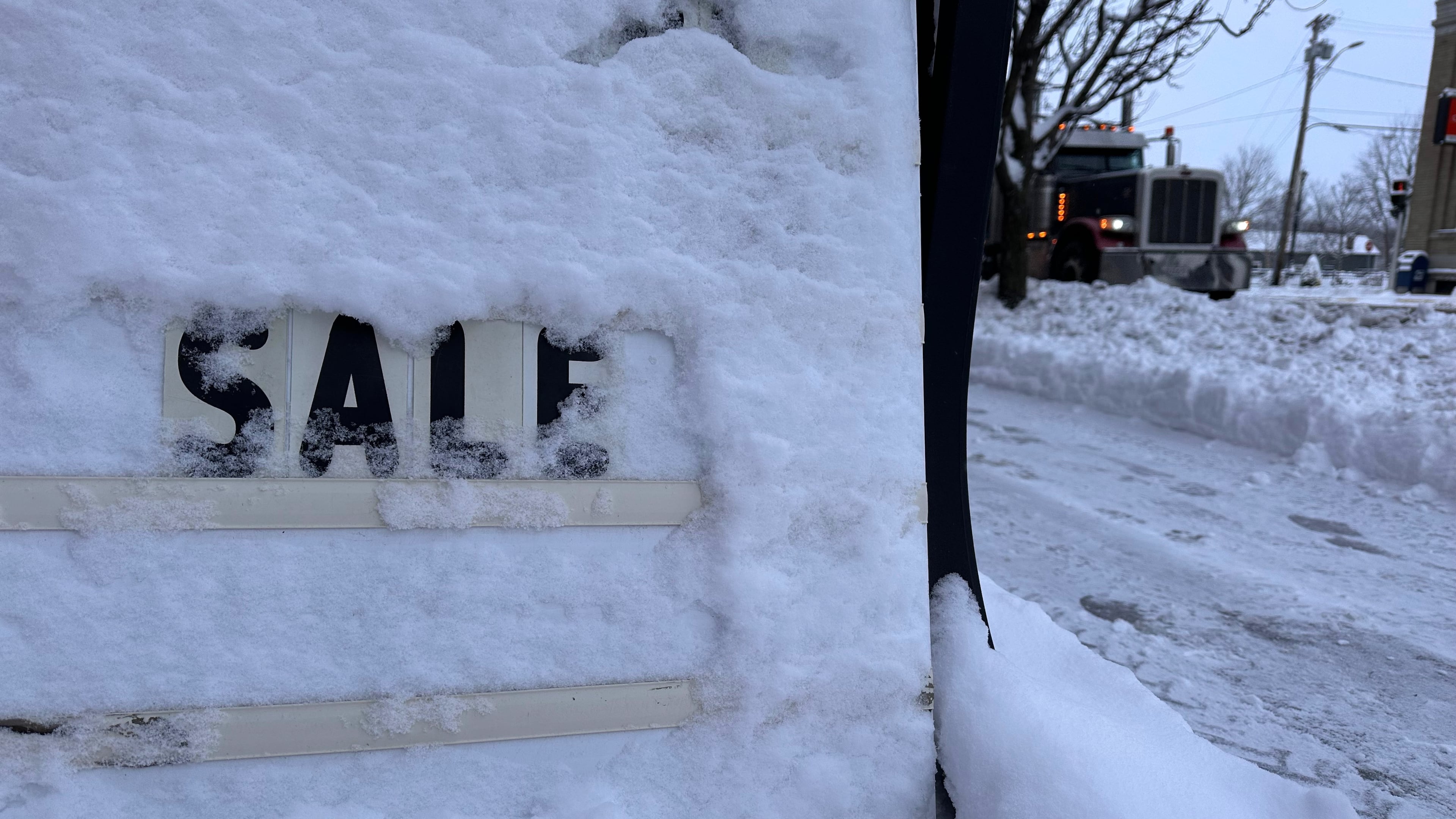 A store's promotional sign is snowed under in Lowville, N.Y., on Friday, Nov. 28, 2025. (AP Photo/Cara Anna)