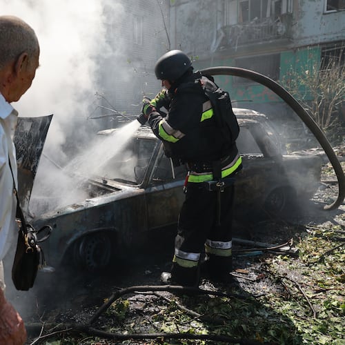 Rescue workers try to put out a fire of a residential building and cars burning after a Russian air guided bomb strike in Zaporizhzhia, Ukraine, Monday, Aug. 10, 2026. (AP Photo/Kateryna Klochko)