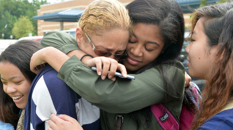 Shanta Watson (in sunglasses) hugs her daughter, Kiara Ross, 15, a sophomore, after they reunited outside Norcross High School on Sept. 11, 2014. At far left is friend Kady Dosunu, 16, and on far right is Jamie Au, 15. Both are also sophomores.