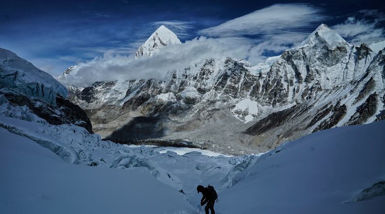 FILE - Mount Pumori, center left, looms in the background as a mountaineer negotiates Khumbu Icefall to descend to Everest Base Camp, in Nepal, May 4, 2025. (AP Photo/Pasang Rinzee Sherpa, File)