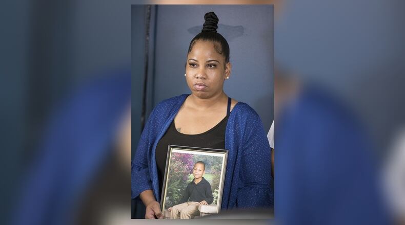 Allison Woods holds a photo of her son Isaiah Payton. The 12-year-old was shot after a football game in August and remains hospitalized. Doctors say he likely won't walk again.