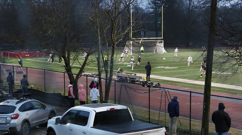 Parents watch their daughters compete in the girls soccer game from the sidewalk outside the fence on Chester Avenue at Maynard Jackson High School on Feb. 18. Atlanta Public Schools lifted its ban on spectators on March 1. Curtis Compton / AJC FILE PHOTO
