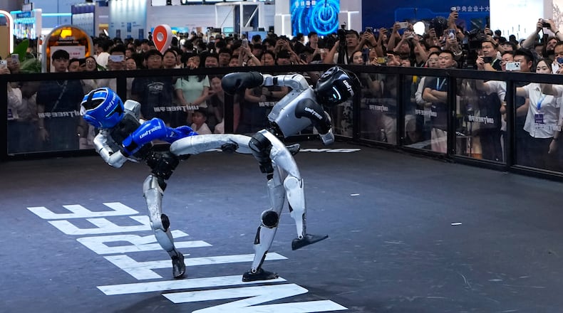 Visitors watch robots demonstrate boxing moves at a booth of Unitree, one of China's largest humanoid robot makers, during the World Robot Conference at the Beijing Yichuang International Convention and Exhibition Centre in Beijing, Wednesday, Aug. 19, 2026. (AP Photo/Andy Wong)