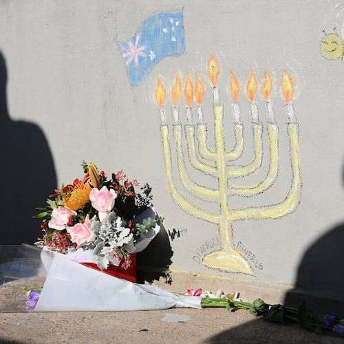 FILE - People walk past a memorial drawn on the wall of a walk bridge as a tribute following Sunday's shooting at Bondi Beach, in Sydney, Friday, Dec. 19, 2025. (AP Photo/Steve Markham, file)