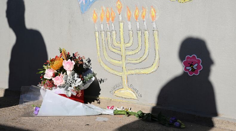 FILE - People walk past a memorial drawn on the wall of a walk bridge as a tribute following Sunday's shooting at Bondi Beach, in Sydney, Friday, Dec. 19, 2025. (AP Photo/Steve Markham, file)