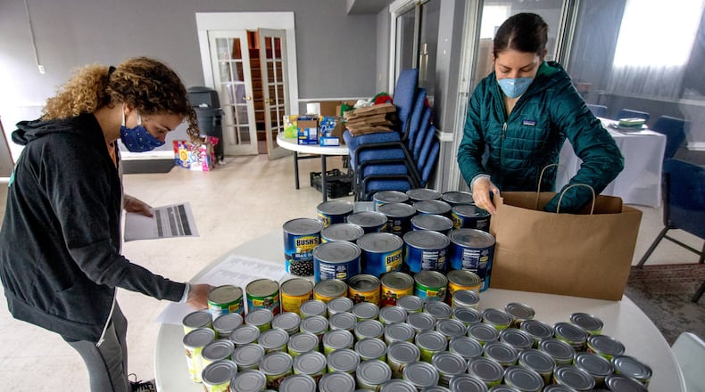 Concrete Jungle volunteers Cecelia Borgman (L) and Savannah Schnall (R) organize meals that will be delivered to Atlanta needy families Monday, April 20, 2020. STEVE SCHAEFER / SPECIAL TO THE AJC
