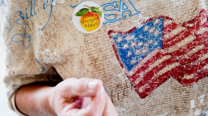 In this March 1, 2016 file photo, Joanna Walters puts on a "I'm a Georgia Voter" sticker on her American flag shirt as she votes during Georgia's primary election at the polling station at South Lowndes Recreation Complex in Lake Park, Ga. ( AP Photo/Andrew Harnik)