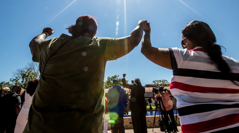 At the King Center on Sunday, April 4, 2021, the Rev. Martin Luther King Jr.'s family holds a wreath-laying ceremony on the 53rd anniversary of the assassination of the civil rights leader. Melinda Latson of Fayettville, N.C. (left), joins hands with a stranger, Sylvia Swindell (right), who sings "We Shall Overcome" with the group. (Photo: Jenni Girtman for The Atlanta Journal-Constitution)